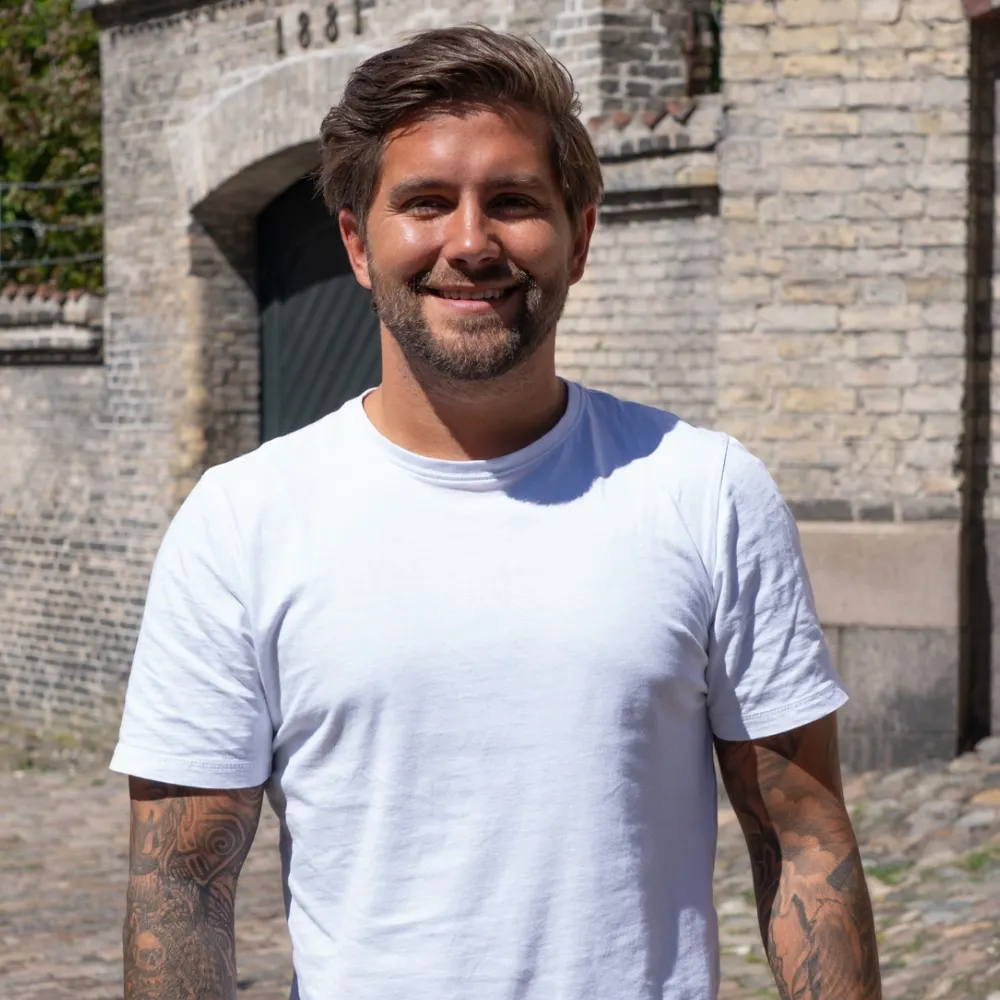 Mads, rådgiver hos Njord Forsikring, foran en murstensbygning