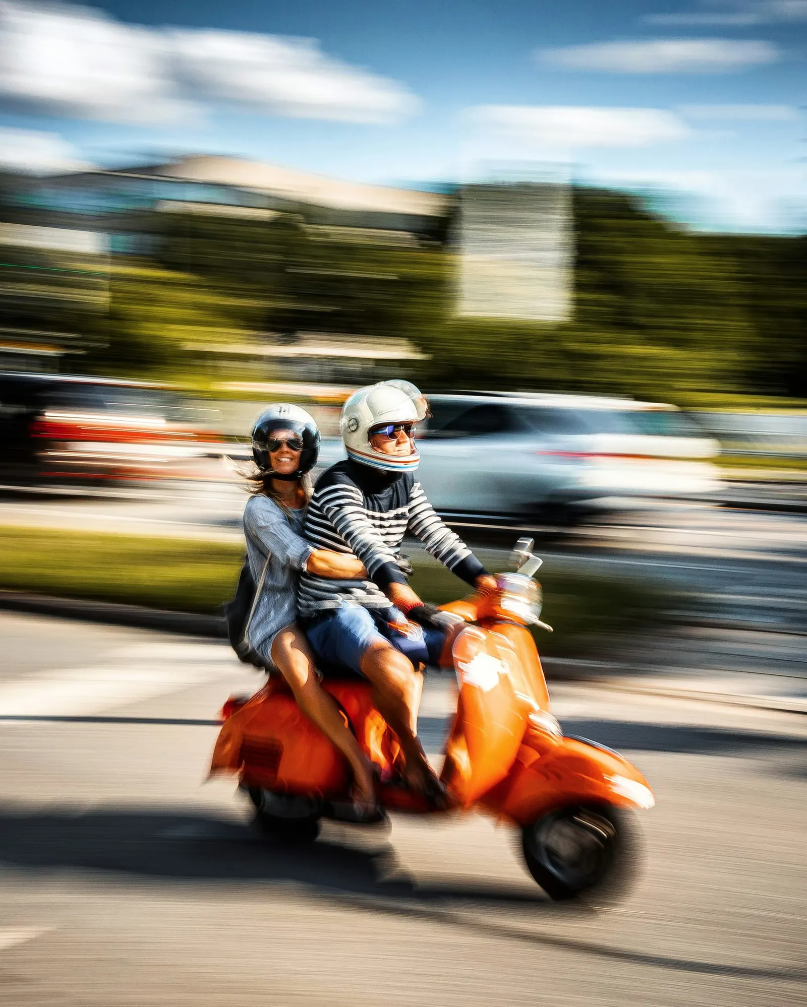 To personer kører på en orange scooter i byen